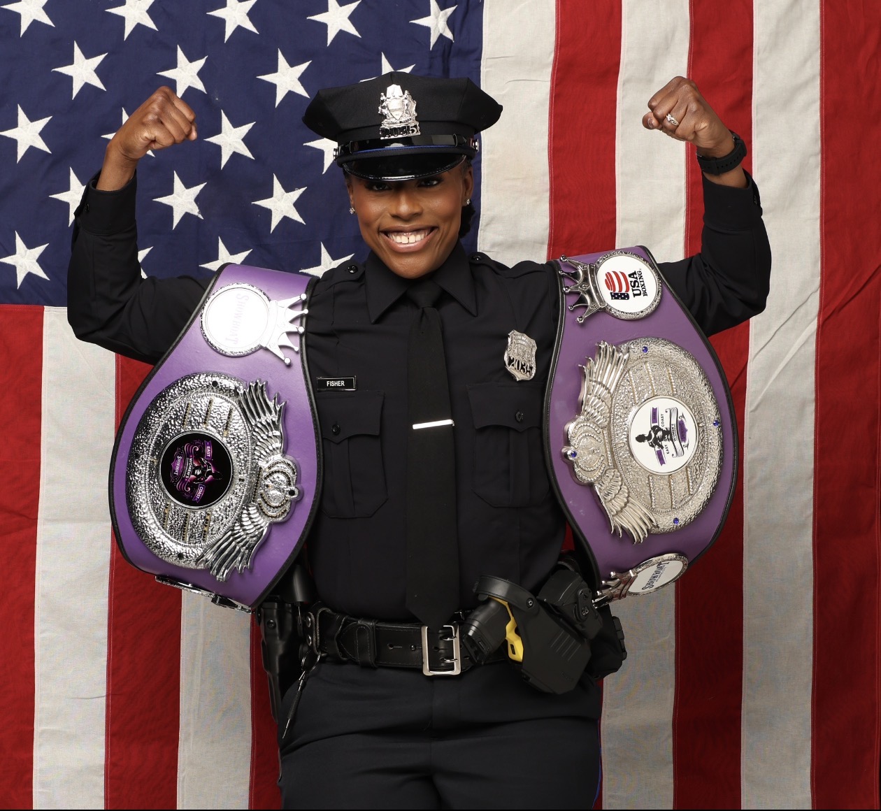 Nicole Fisher in Philadelphia Police uniform holding two championship belts
